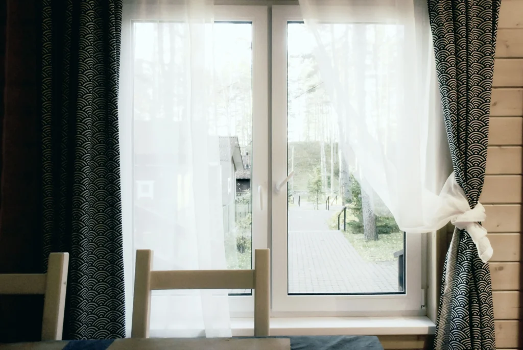White casement windows with sheer curtains and garden view